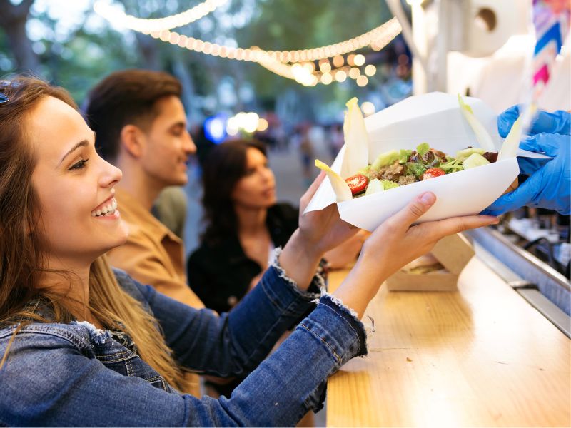 Girl accepting her plate of street food from a street food vendor.