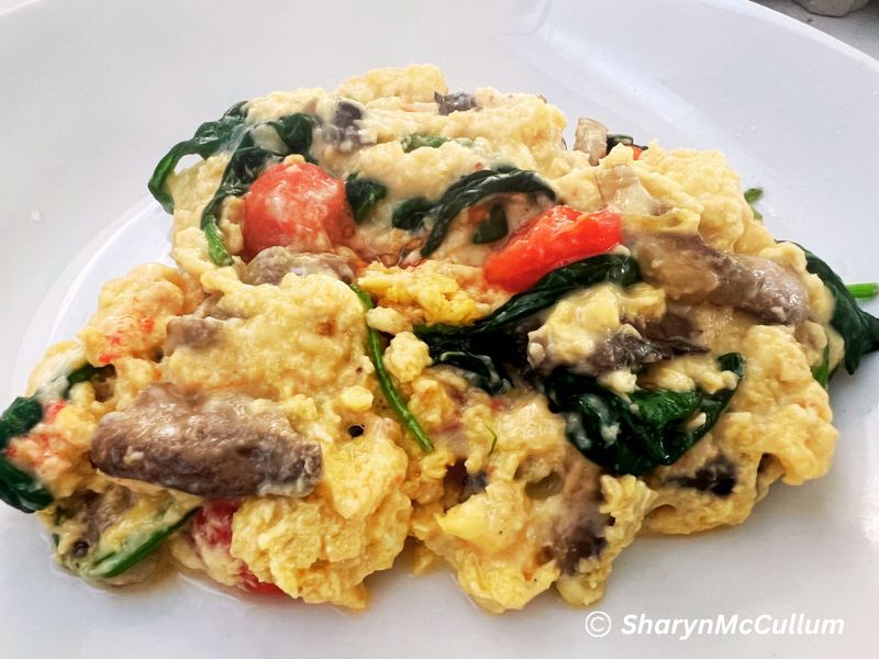 Loaded scrambled eggs. Eggs scrambled with tomato, bacon, onion and spinach mixed through the egg.