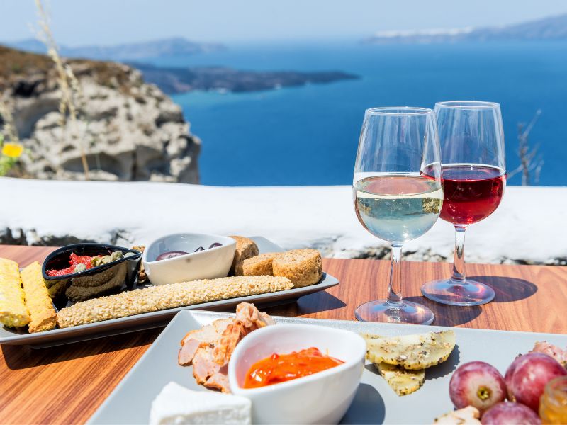 Traditional favourite Greek foods with a glass of wine and a view over the Mediterranean.