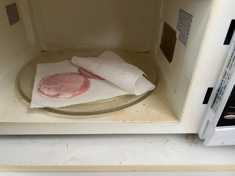bacon slices between paper towel for cooking in a microwave