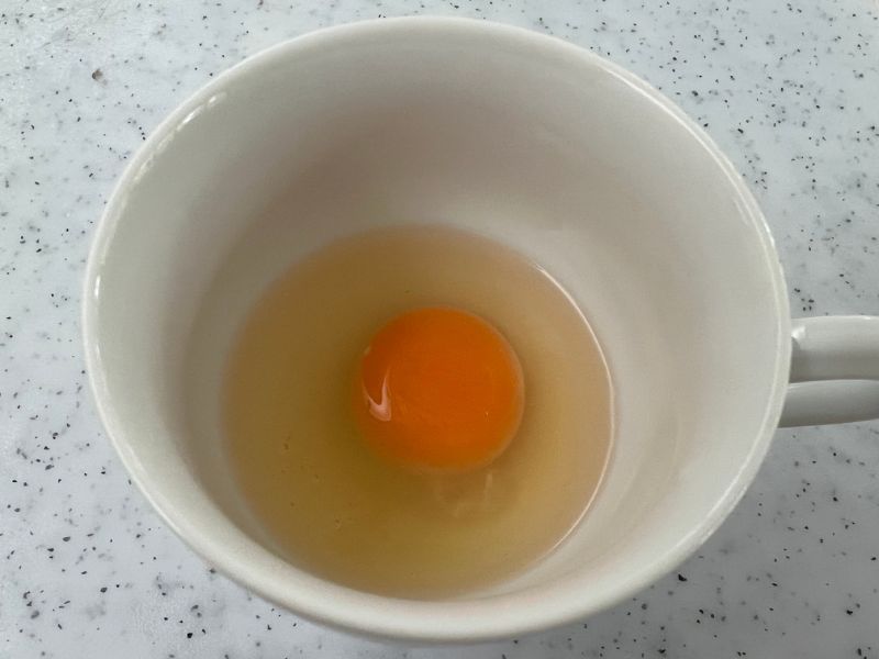 egg broken in a cup for microwaving