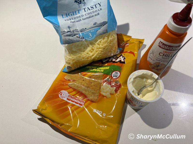 simple ingredients for a Nachos - tortilla chips, cheese, sour cream and sweet chilli sauce